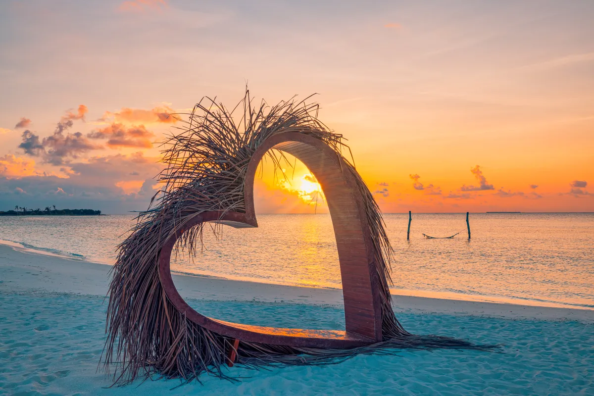 Heart-shaped beach arch at sunset, romantic getaway